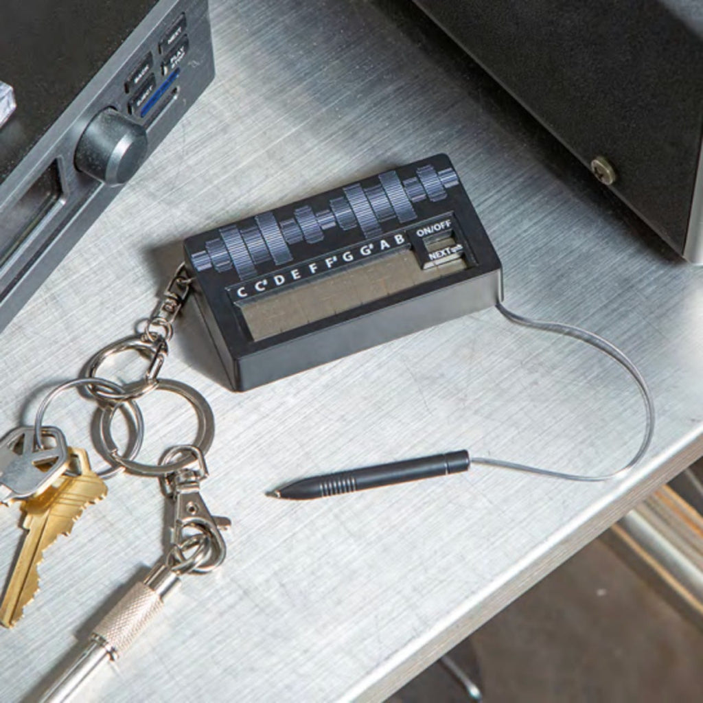 Small electronic device on a desk with keys and a pen nearby